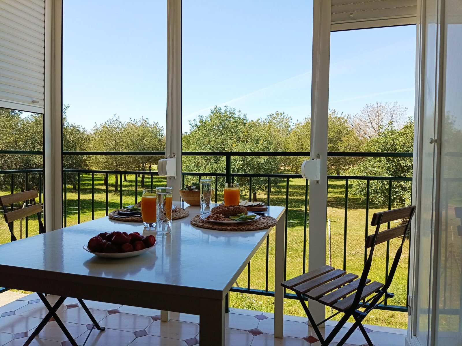 Mesa preparada junto al balcón, con vistas a una zona arbolada
