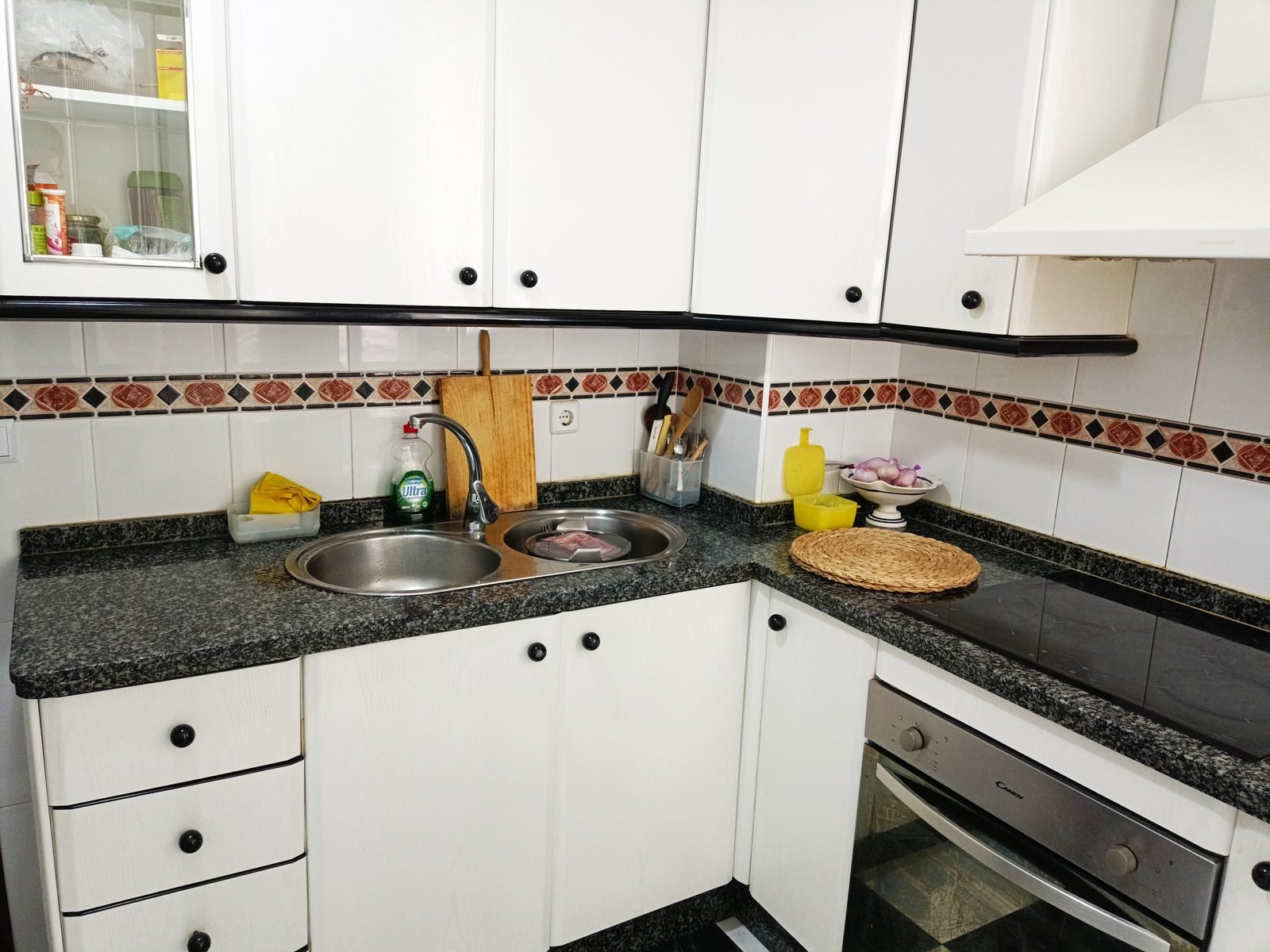 Cocina con fregadero, encimera oscura y horno