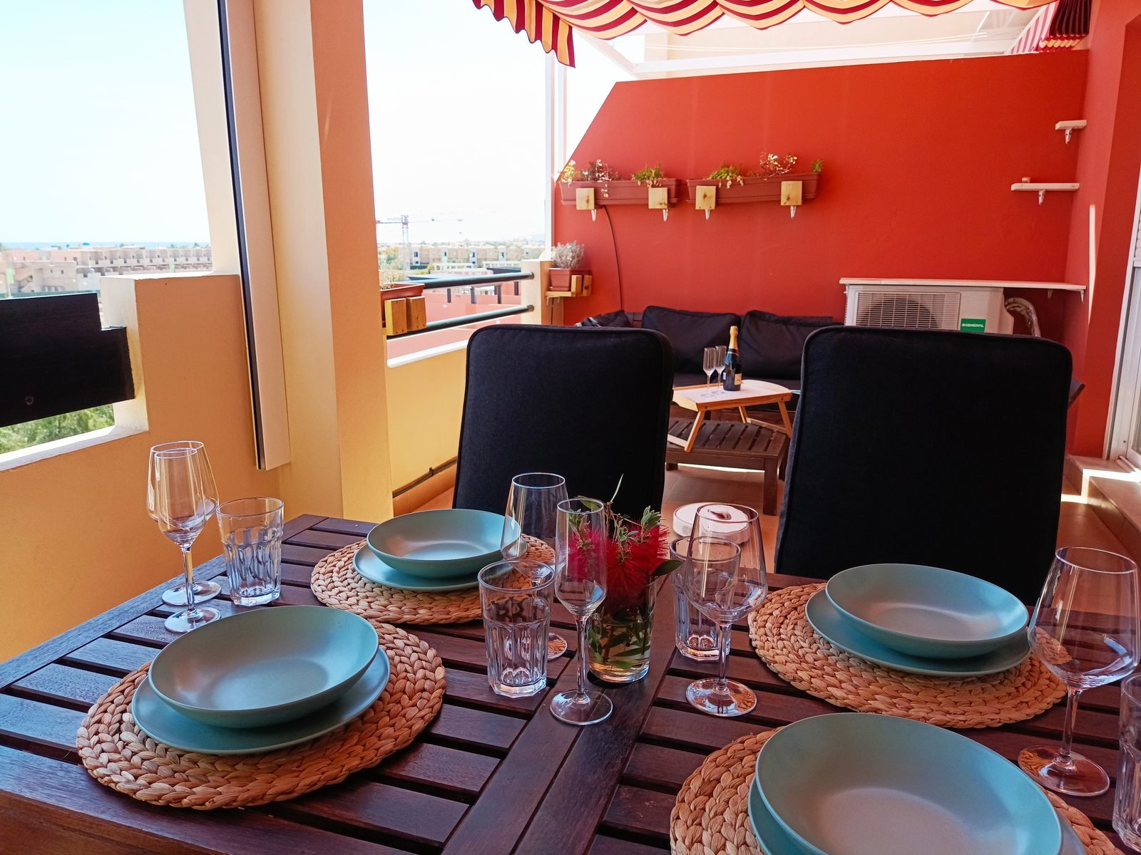Terrace with a laid wooden table, chairs and an awning