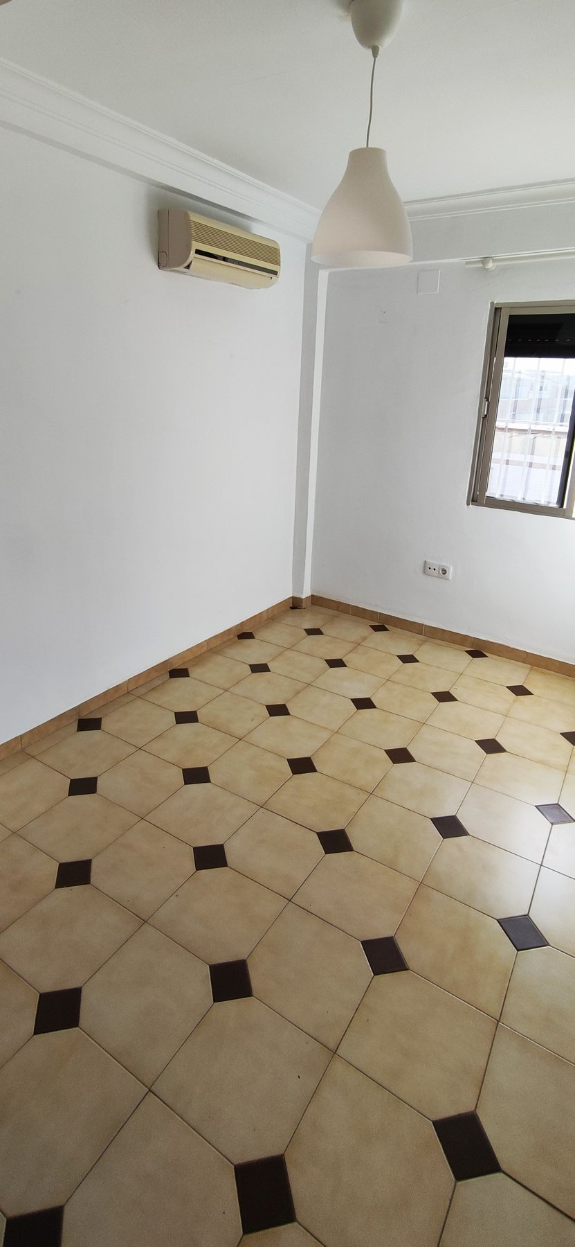 Empty room with an air conditioning unit, lamp and window