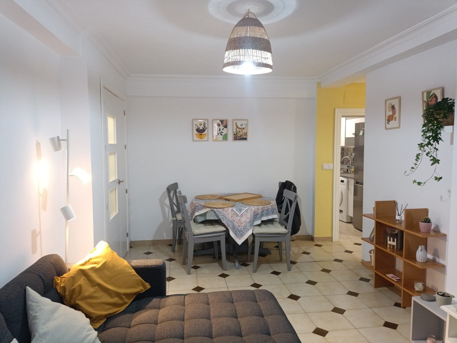 Living room with a sofa and dining table, with a doorway to the kitchen
