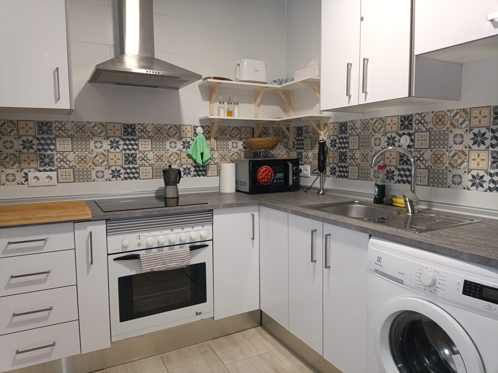 Kitchen with white units, decorative tiles, oven and washing machine