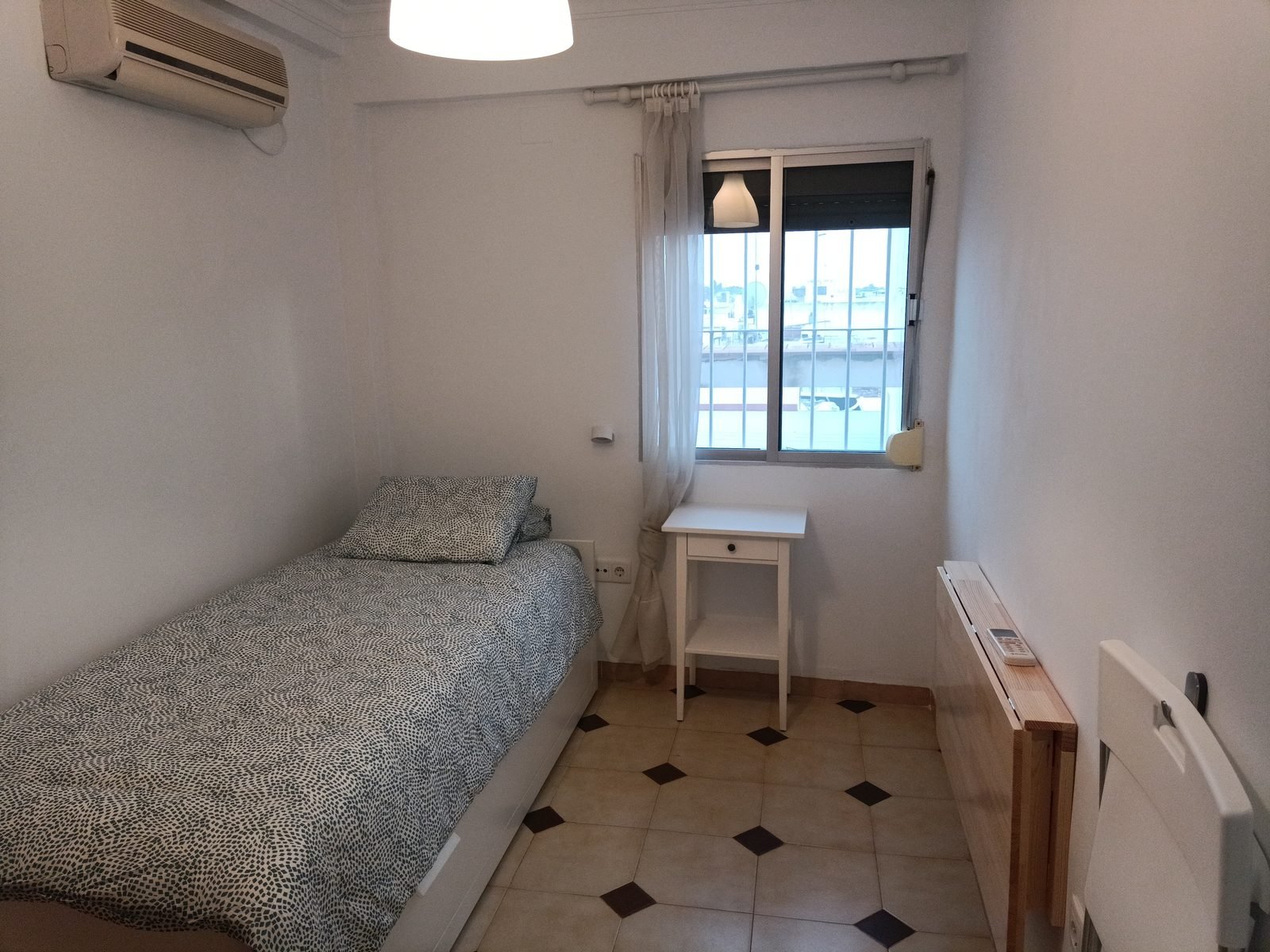 The same room with a bed, bedside table and fold-down table
