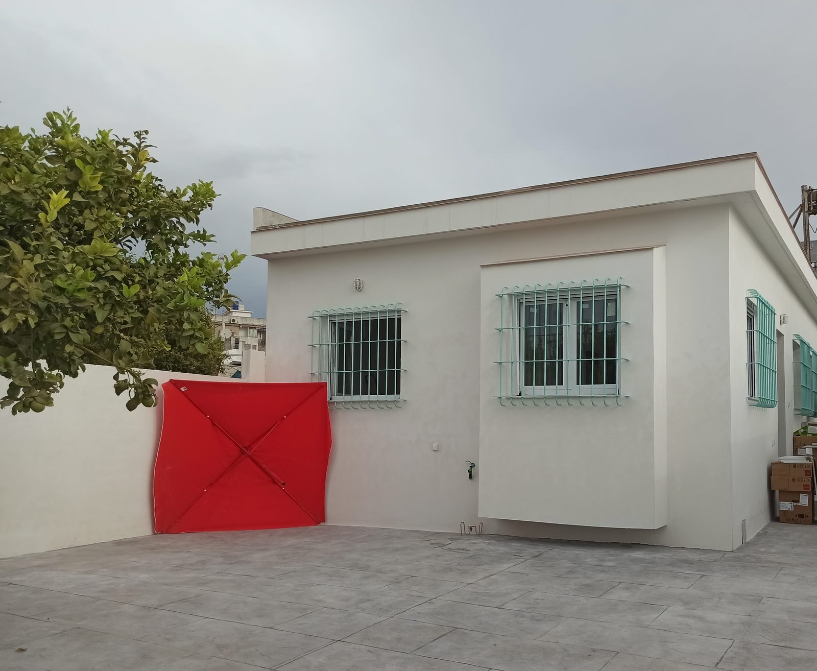 Fachada blanca con rejas verde agua, abierta al patio
