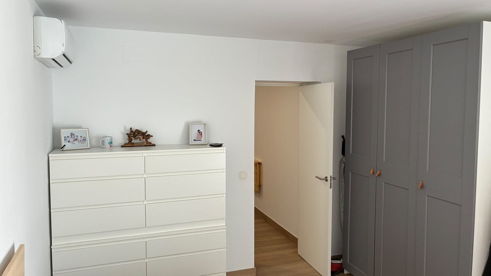 Dormitorio con cómoda blanca, armario y aire acondicionado