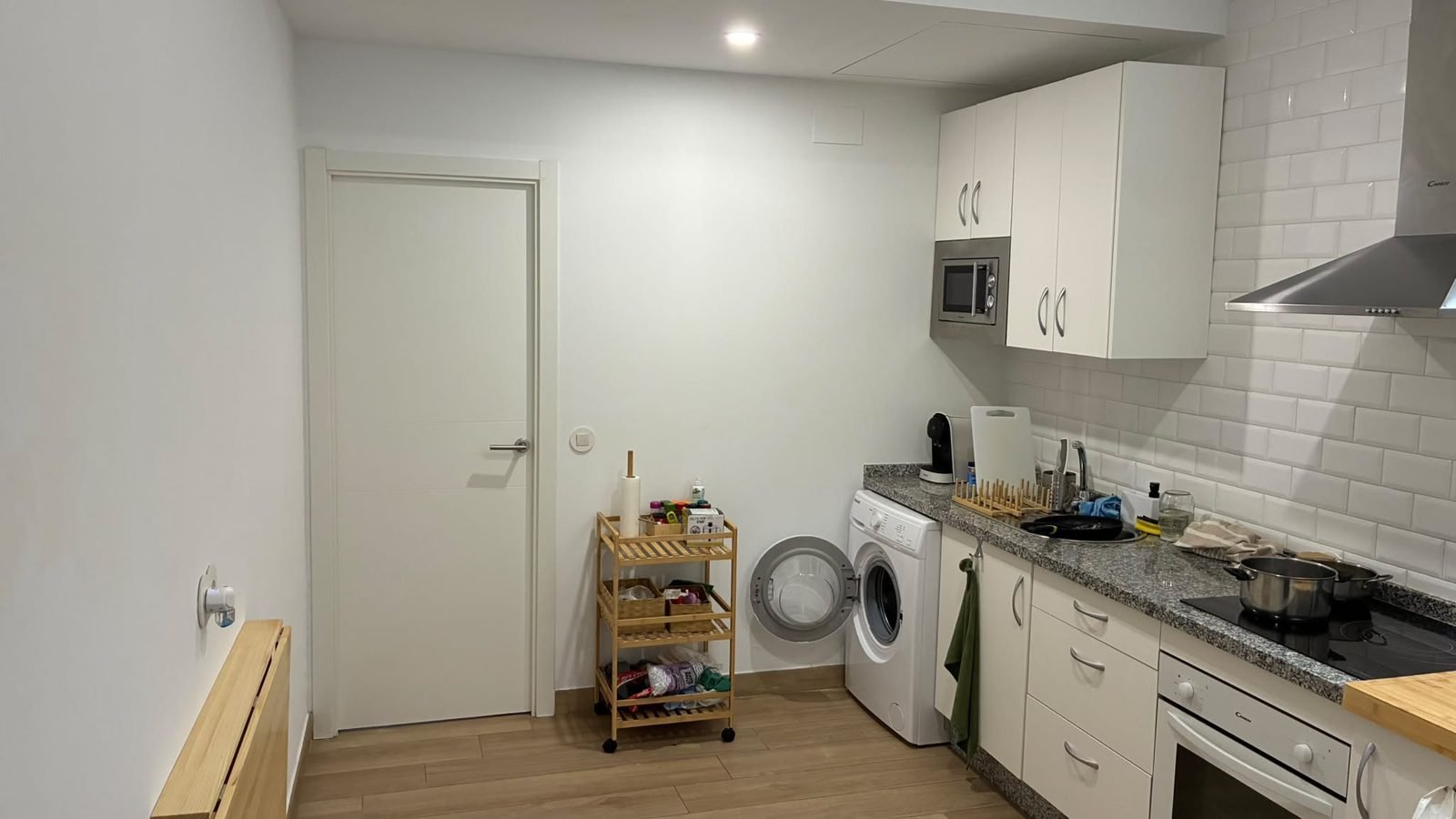 Cocina con muebles blancos, campana y lavadora