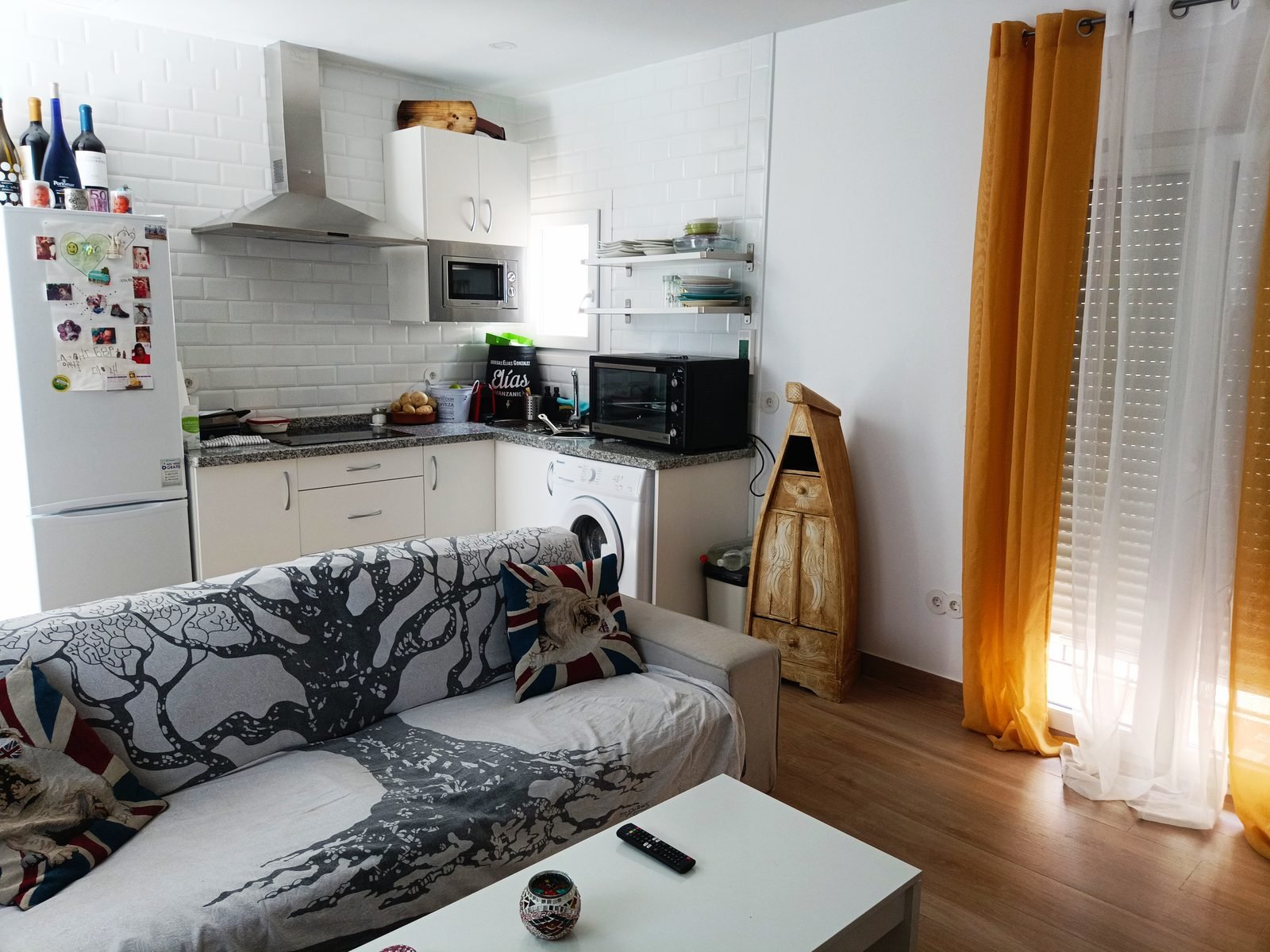 Cocina abierta al salón, con sofá y cortinas