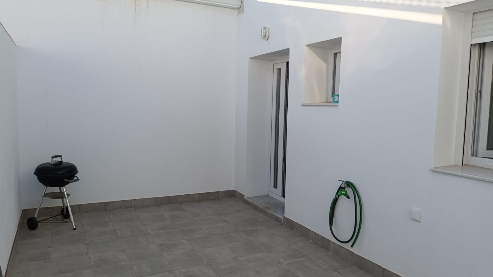 Patio de uno de los bajos, con suelo de baldosa y paredes blancas