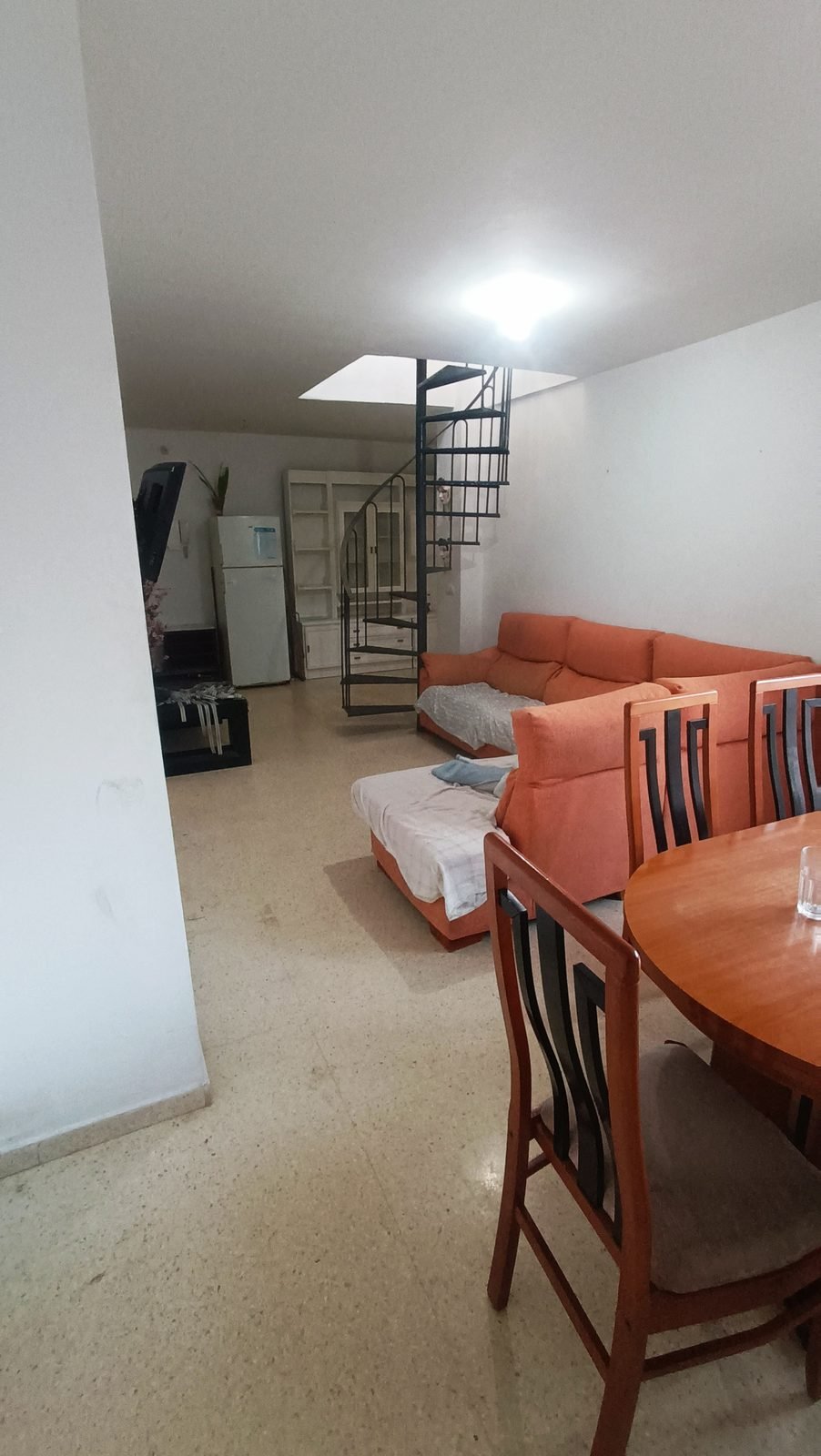 Salón con sofás antiguos, mesa de comedor y escalera de caracol
