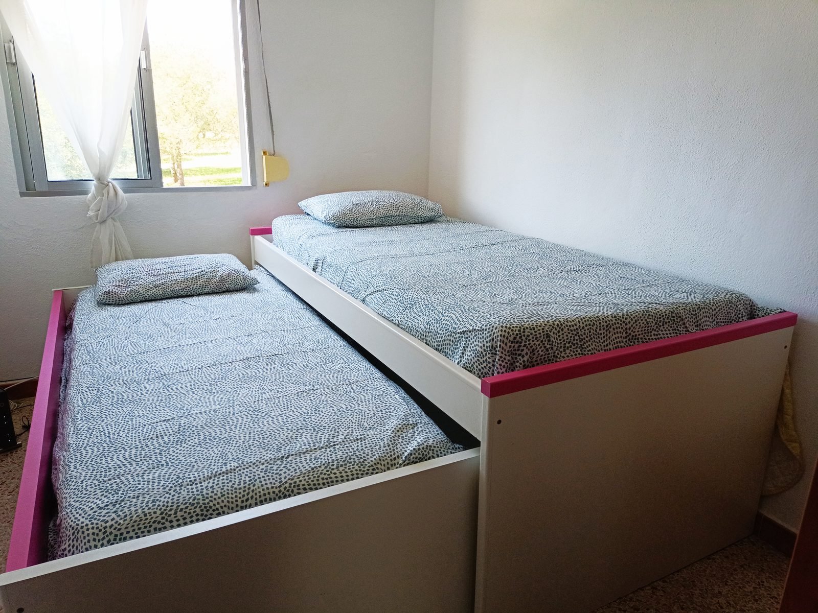 Dormitorio con cama nido de dos camas y ventana