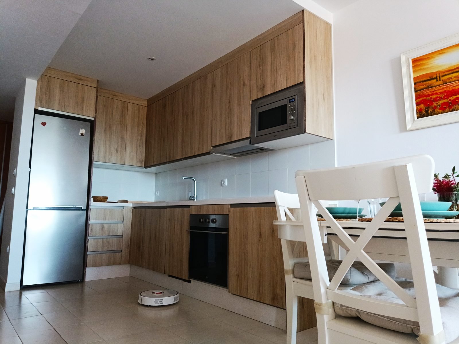 Cocina con muebles de madera, frigorífico y mesa de comedor
