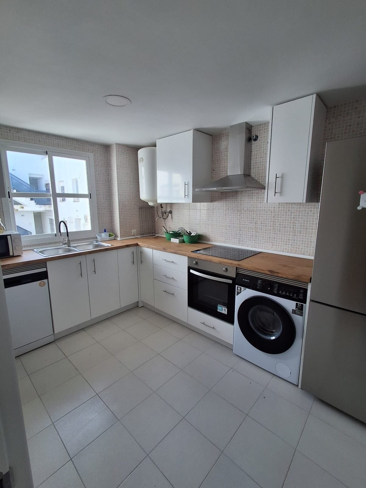 Cocina nueva con muebles blancos, encimera de madera y electrodomésticos